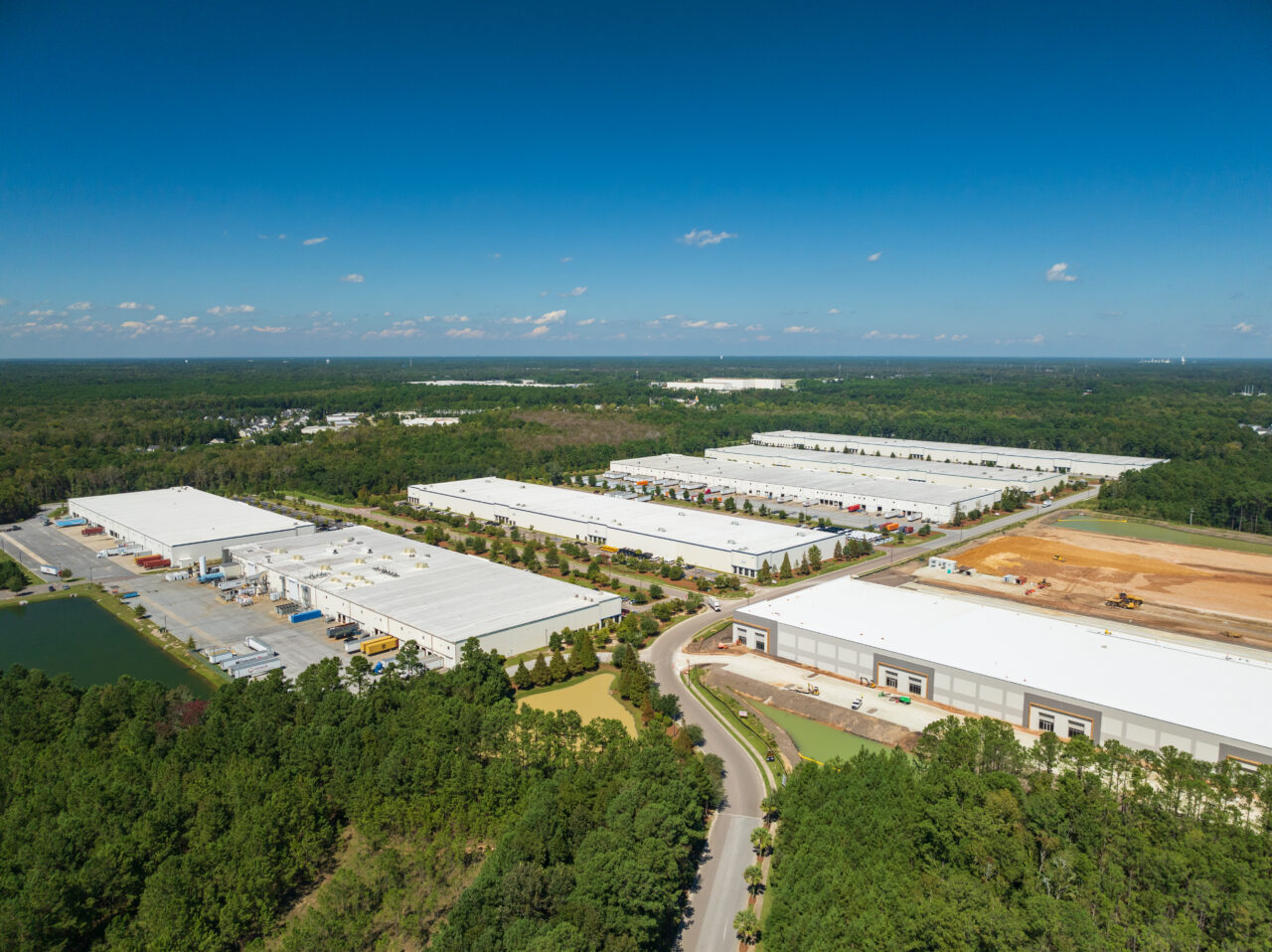 Aerial view of a large industrial park with warehouses and distribution centers surrounded by forest.