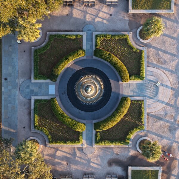 Top-down aerial view of a symmetrical formal garden with a circular fountain at its center.