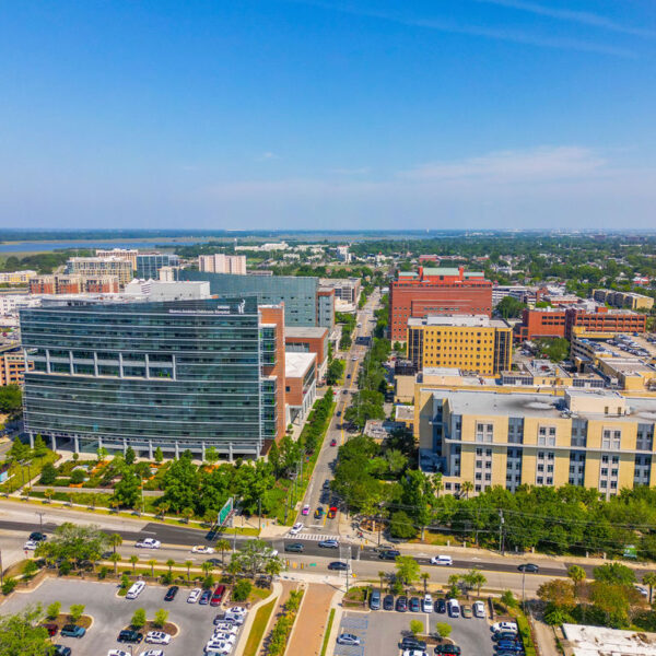 Aerial view of a modern hospital complex and urban medical district with a waterfront in the background on a sunny day.