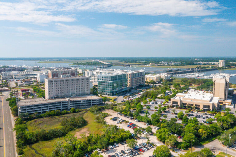 Aerial view of a waterfront commercial district with office buildings, marina, and parking lots.
