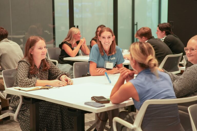 Group of women talking at tables during a networking event.