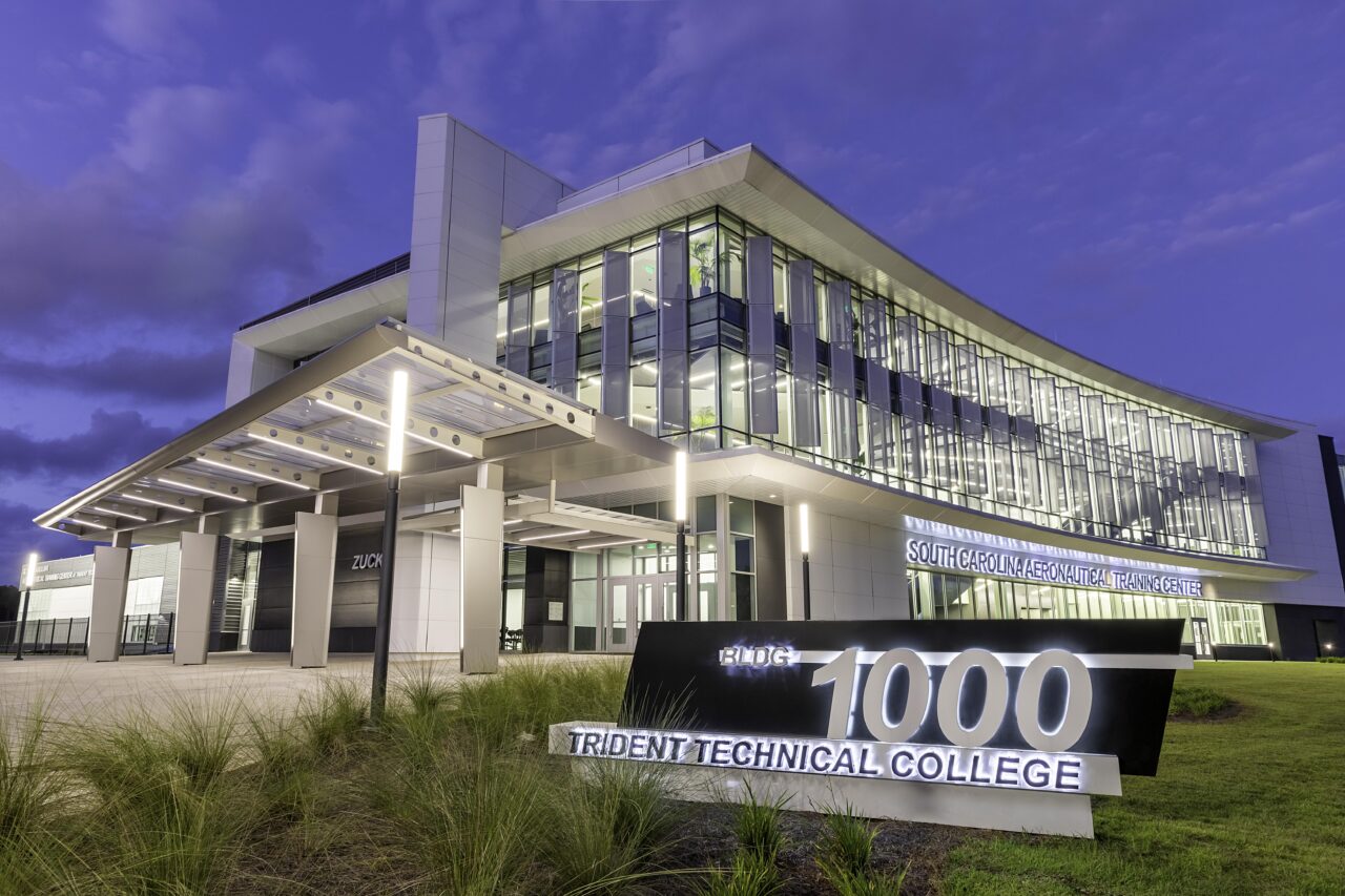 Modern glass college building with a "Building 1000" sign at twilight.