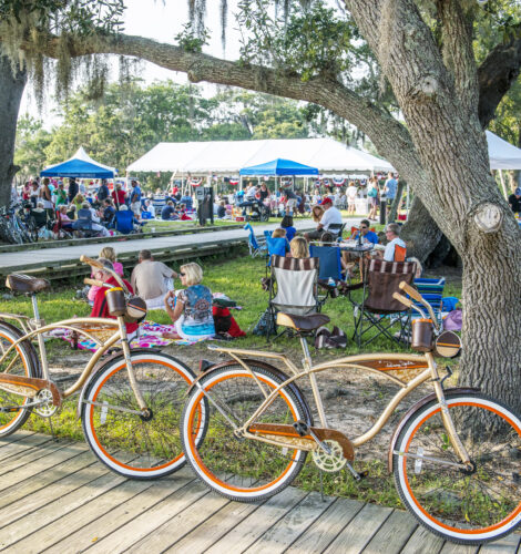 A large crowd sits outside during a summertime festival.
