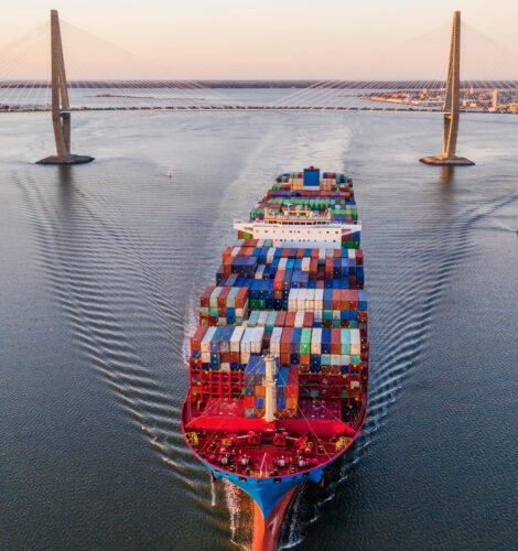 A cargo ship passes under the Ravenel Jr. Bridge in South Carolina at dusk.