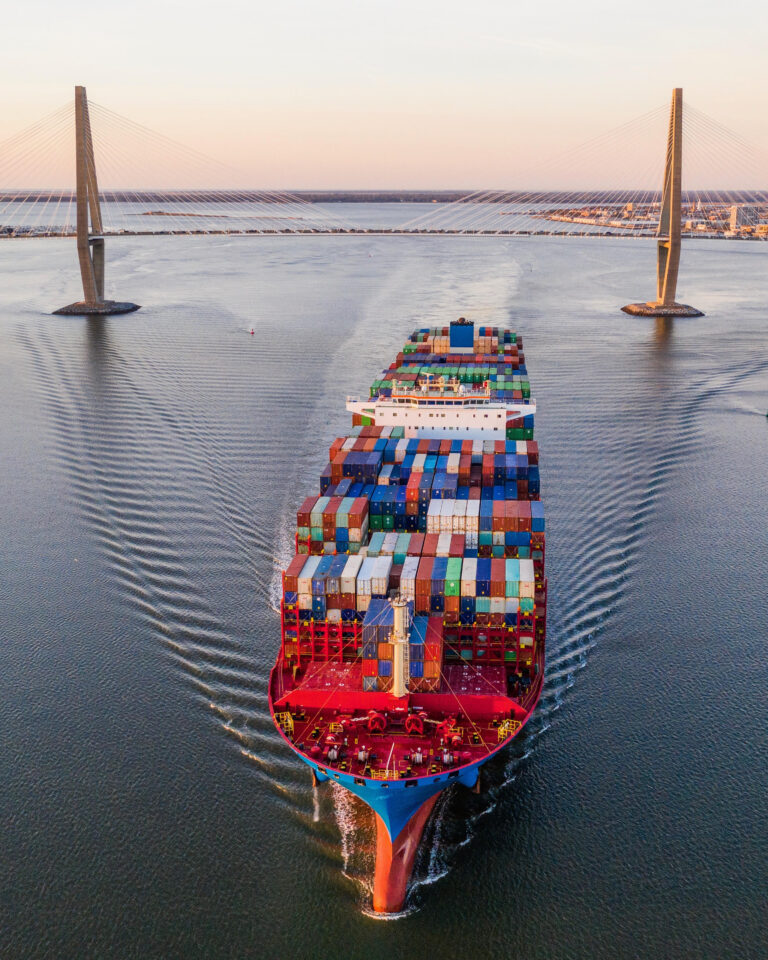 A cargo ship passes under the Ravenel Jr. Bridge in South Carolina at dusk.