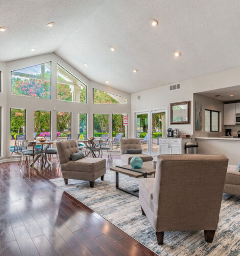 A large living room with floor-to-ceiling windows overlooking a swimming pool.