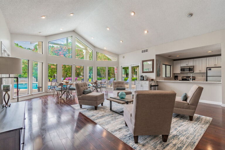 A large living room with floor-to-ceiling windows overlooking a swimming pool.