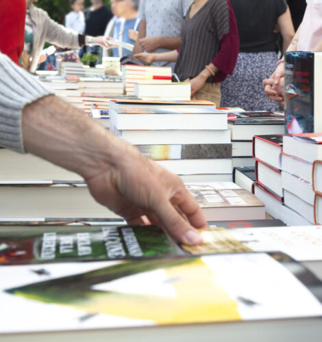 A close-up of people browsing books at an outdoor bookstore.