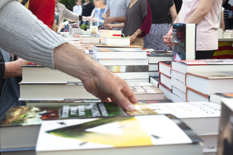A close-up of people browsing books at an outdoor bookstore.