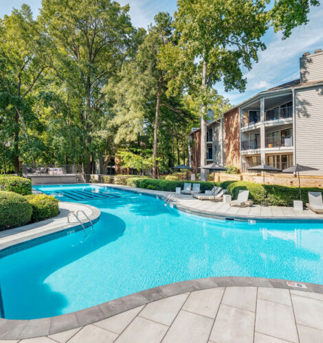 A large swimming pool in an apartment complex during the day.
