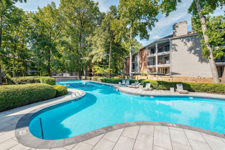 A large swimming pool in an apartment complex during the day.