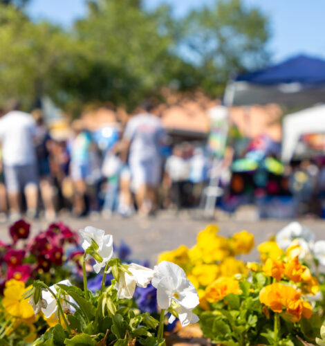 A crowd of people at a festival with flowers.