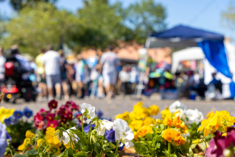 A crowd of people at a festival with flowers.