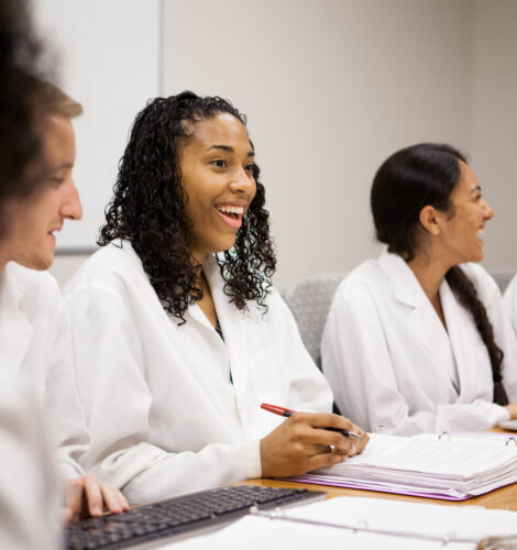 A medical student smiles while at a table with her peers.