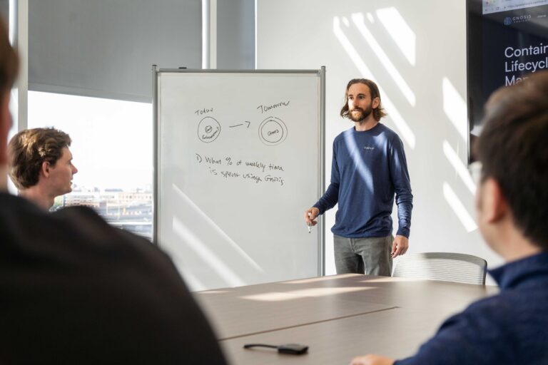 A man uses a whiteboard to give a presentation in a boardroom during the day.