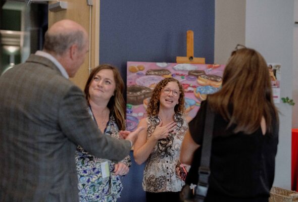 A group of coworkers smile and talk with each other.