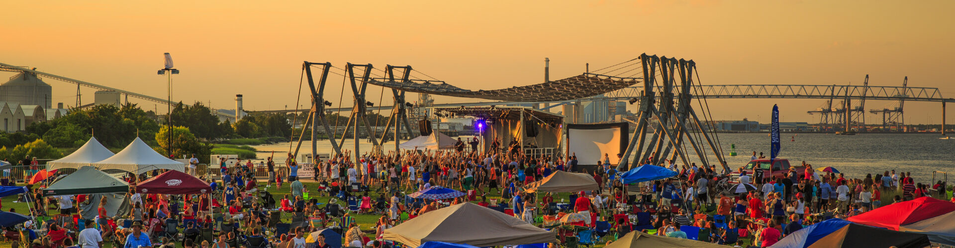 A large crowd of people at a festival in Charleston at dusk.