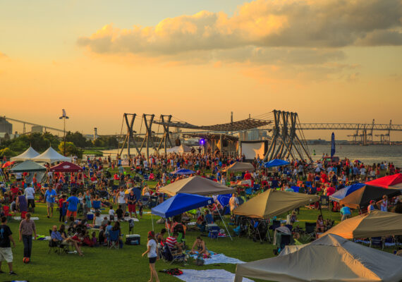 A large crowd of people at a festival in Charleston at dusk.