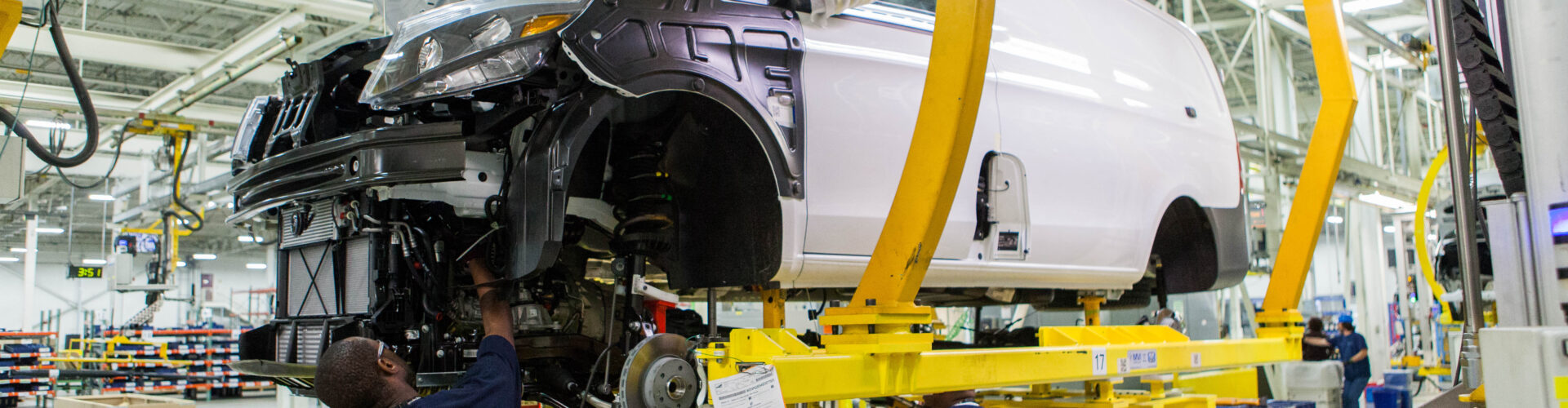 A manufacturing employee works on the body of a car in a factory.