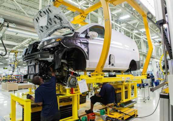 A manufacturing employee works on the body of a car in a factory.
