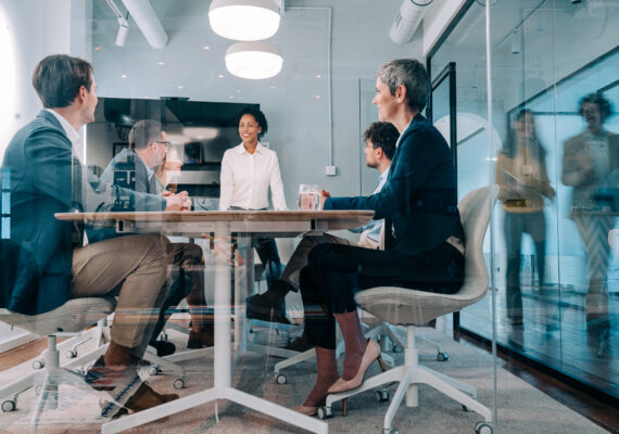 A team of business people sit around a conference table.