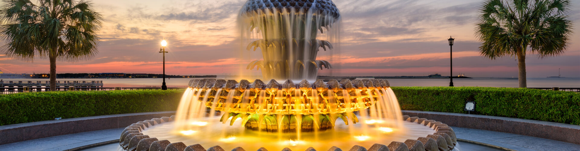 An ornate water fountain lights up at dusk.