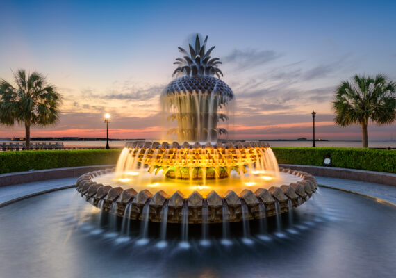 An ornate water fountain lights up at dusk.