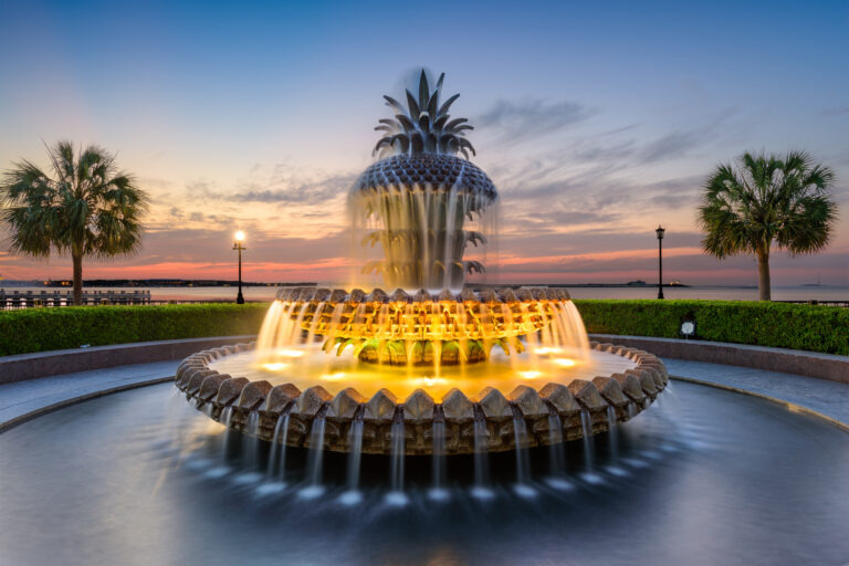 An ornate water fountain lights up at dusk.