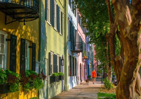 A rman walks his dog in front of a row of colorful townhouses in the Charleston region.