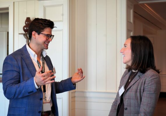 Two business people smile and converse with each other,