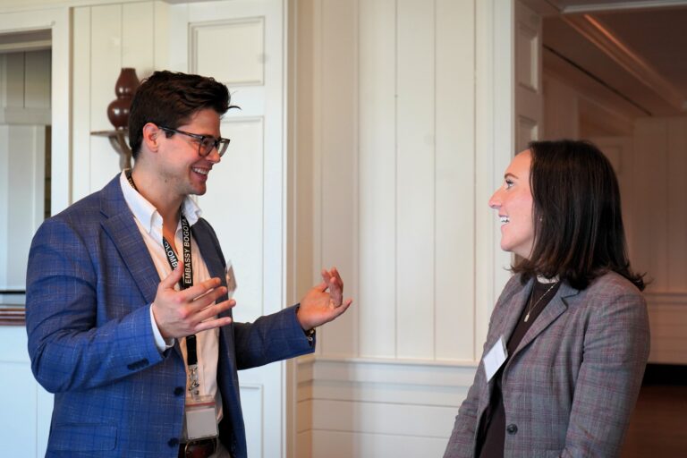 Two business people smile and converse with each other,