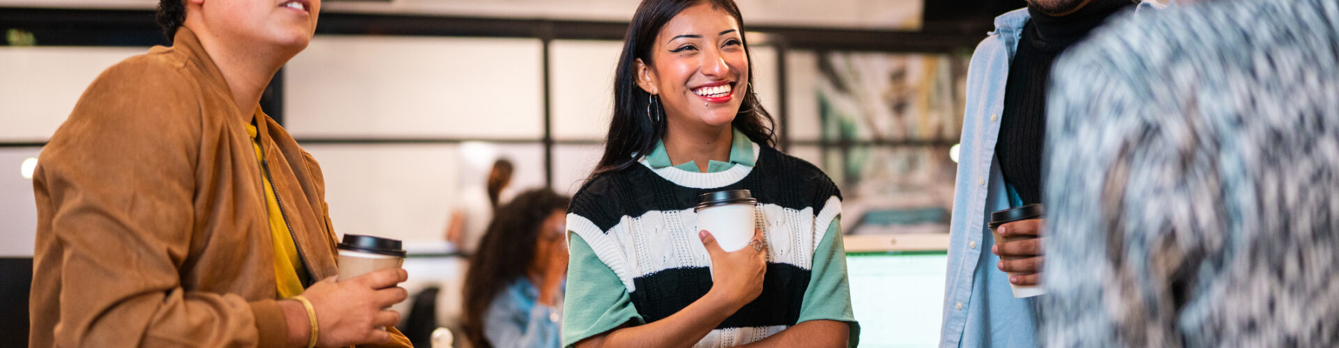 A group of diverse young people converse in a modern office.
