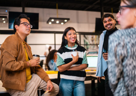 A group of diverse young people converse in a modern office.