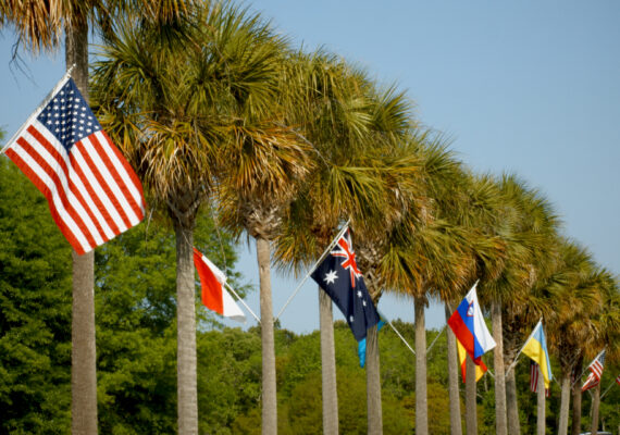Flags from around the world line palm trees on a road.