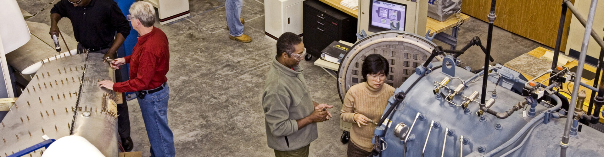 An overhead view of a group of people working in an aircraft training facility together.