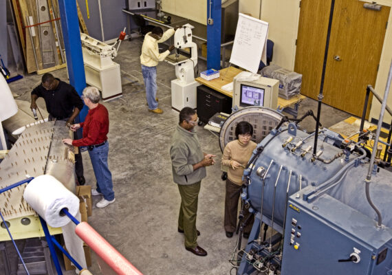 An overhead view of a group of people working in an aircraft training facility together.