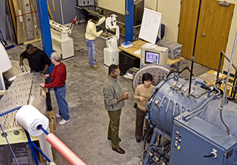 An overhead view of a group of people working in an aircraft training facility together.