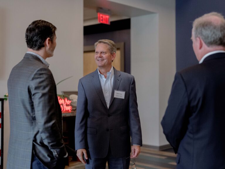 Three business men converse with each other.