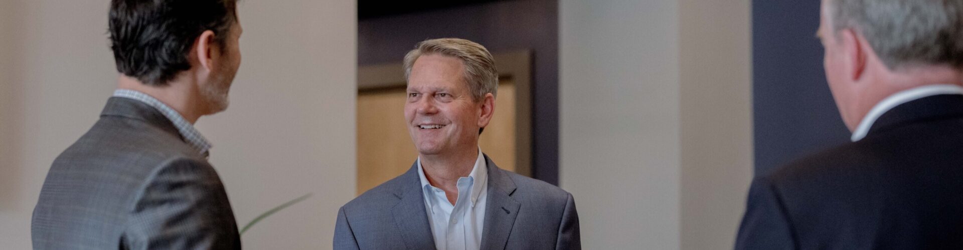 Three business men converse with each other.