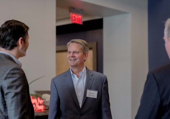 Three business men converse with each other.