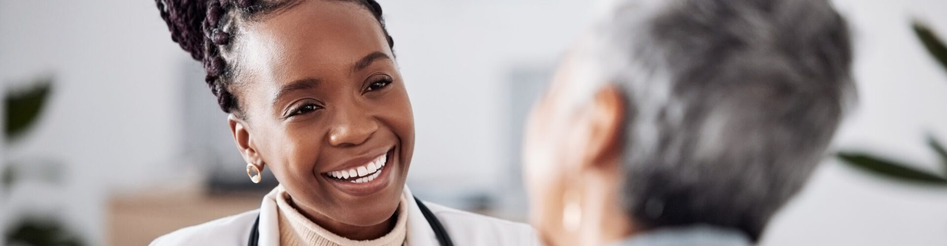 A female doctor smiles while speaking to a patient in a hospital.