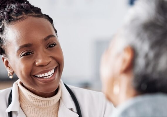 A female doctor smiles while speaking to a patient in a hospital.