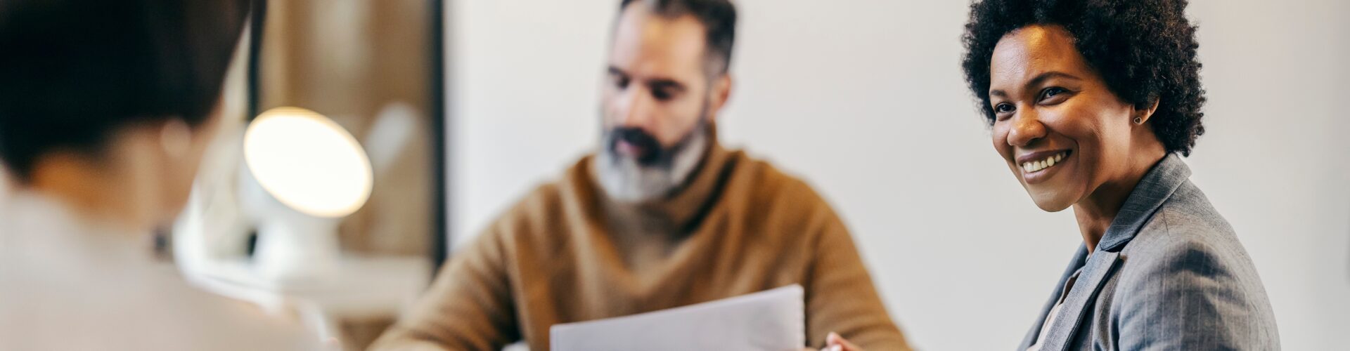A business woman smiles at her coworker while at a table together.