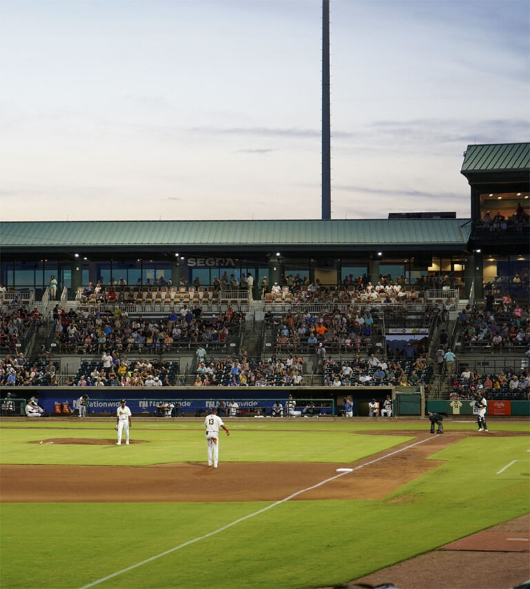 Outfield view of a baseball stadium with players in motion and specators in the background