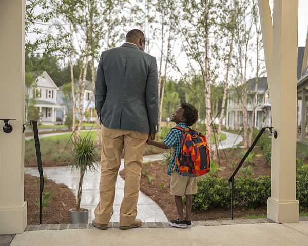 A father walks his child to school along a neighborhood path.