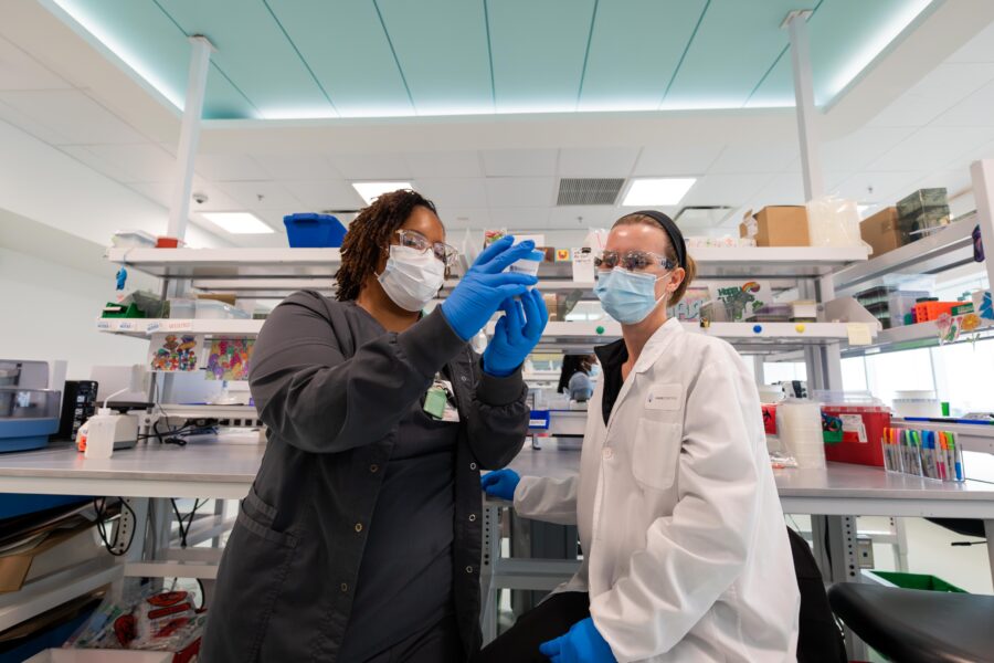 Two biomedical professionals look at a sample together in a lab.