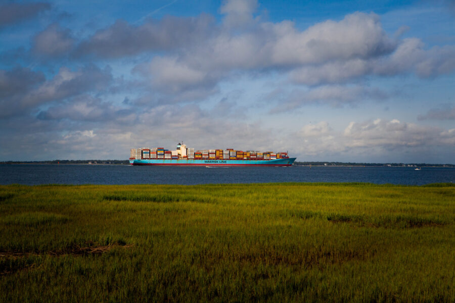 A shipping container sails on the ocean during the day.