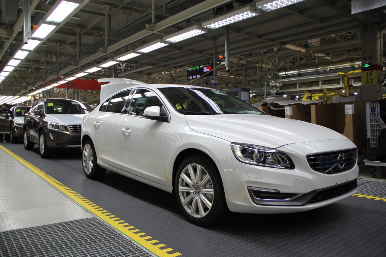 A white Volvo car sits on a production line in a factory.