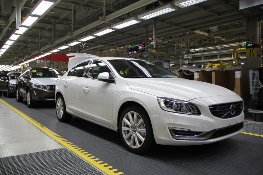 A white Volvo car sits on a production line in a factory.
