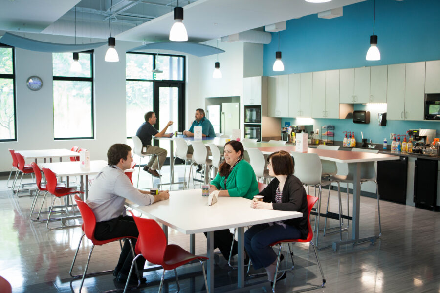 Coworkers sit in a modern office kitchen together.